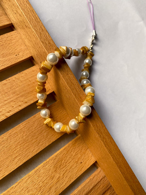 Close-up of golden amber chip beads on a beaded phone strap