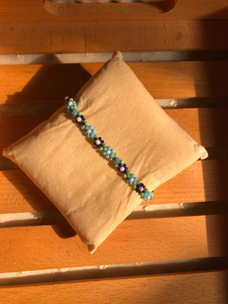 Handmade sky blue daisy seed bead bracelet on deep navy base with white centers