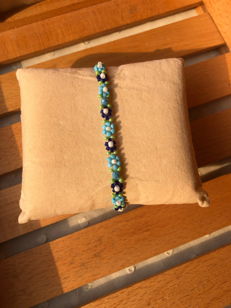 Close-up of blue seed bead daisy flowers with white centers and green accent beads