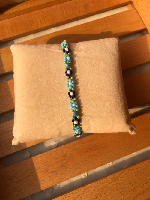 Close-up of blue seed bead daisy flowers with white centers and green accent beads