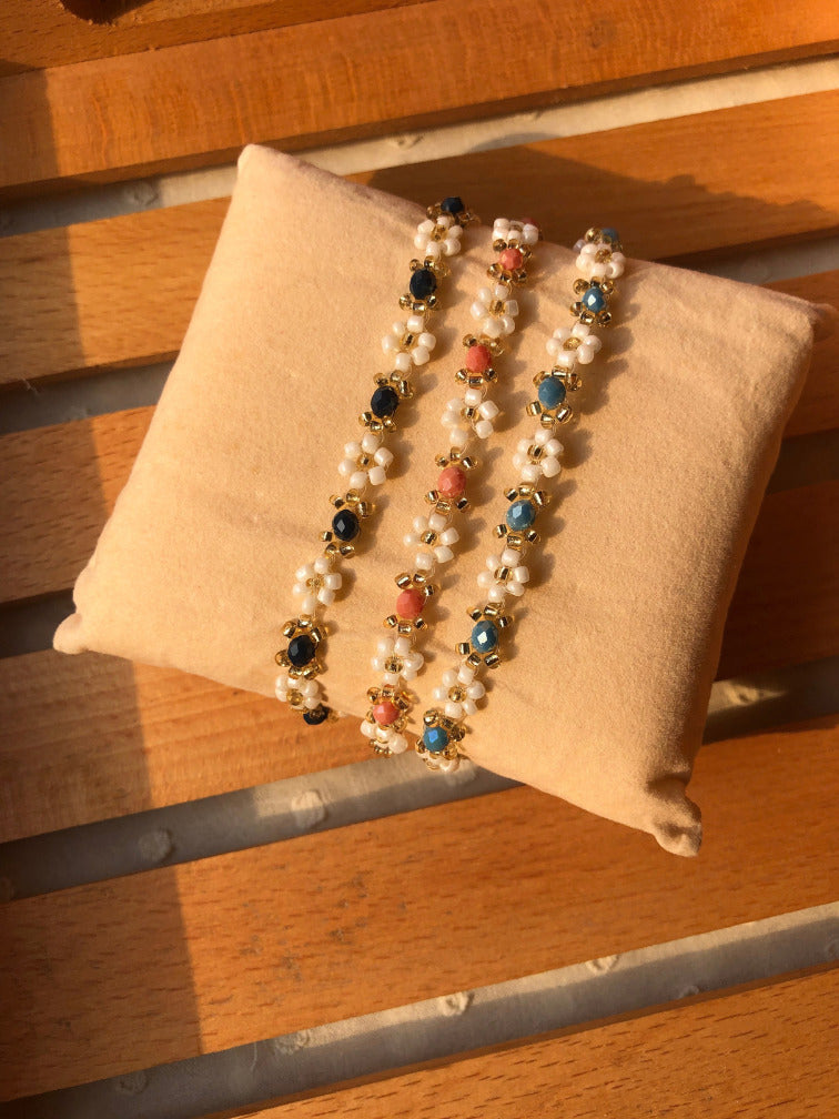 Handmade daisy beaded bracelet set of 3 in navy, coral pink and blue on cream velvet cushion