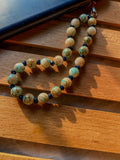 Boho stone bead phone charm resting on dark phone case