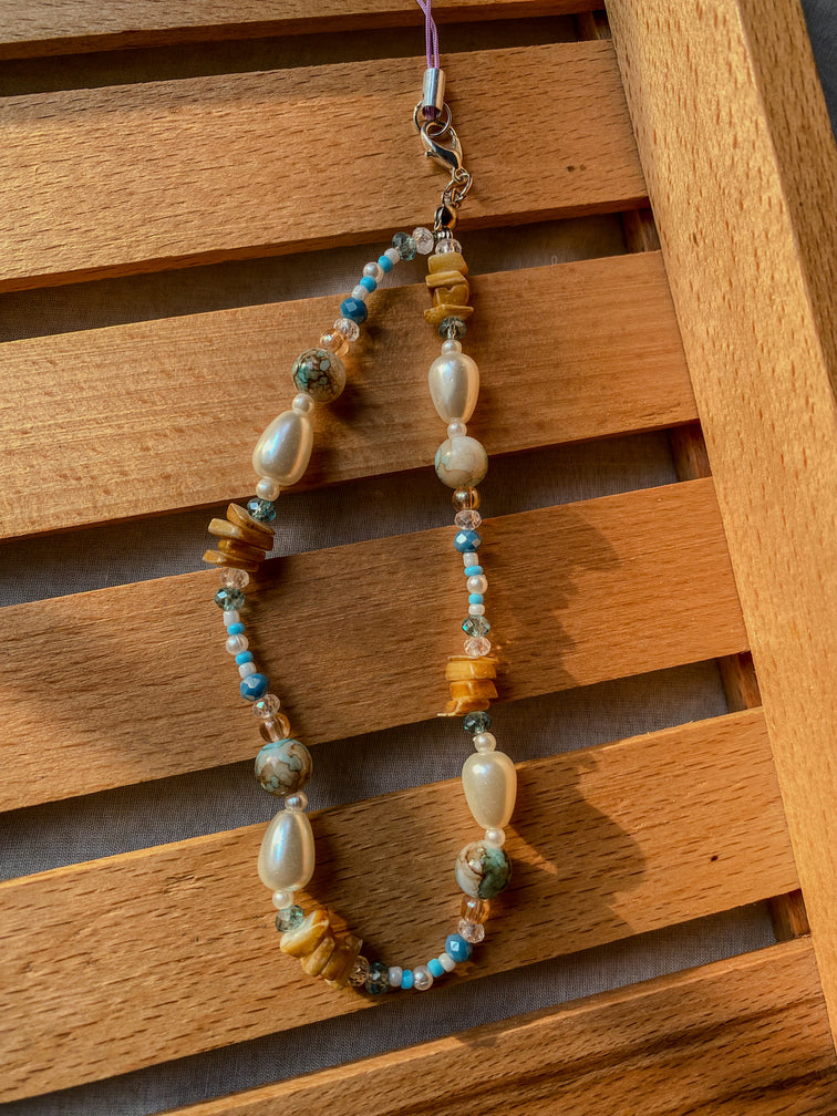 Beaded phone charm with colorful beads on a wooden surface