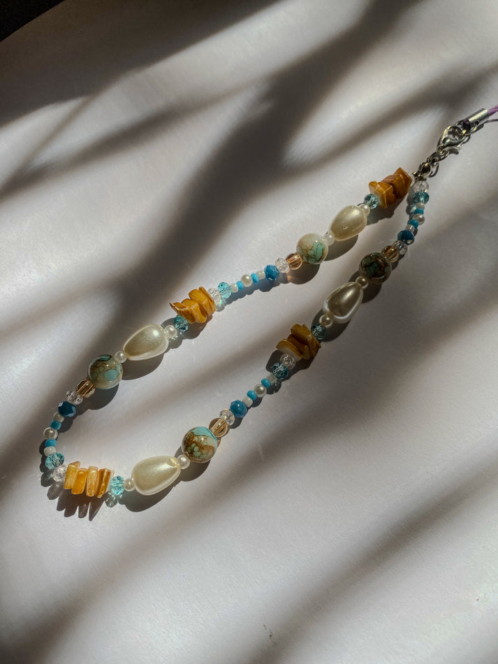 Beaded phone charm with multicolored beads on a light background