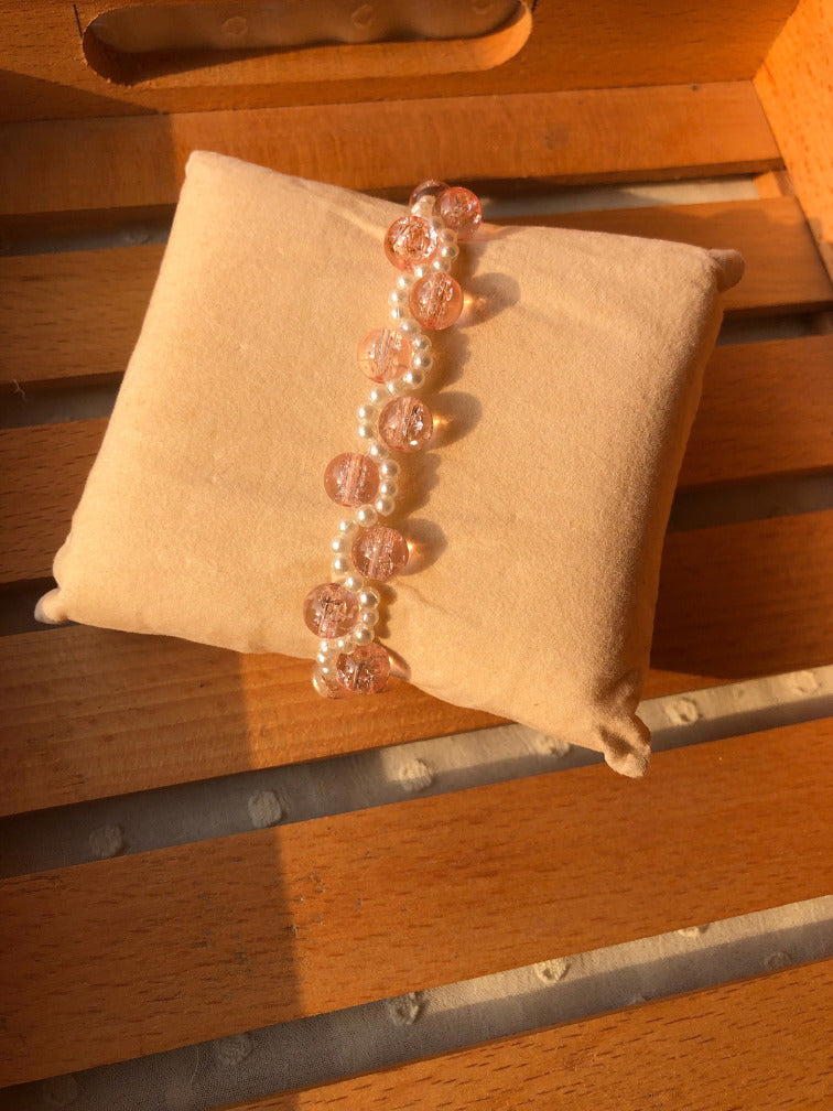 Handmade pink crackle glass and white pearl halo bracelet on cream velvet cushion