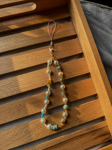 Close-up of turquoise stone beads and golden glass accents on phone strap