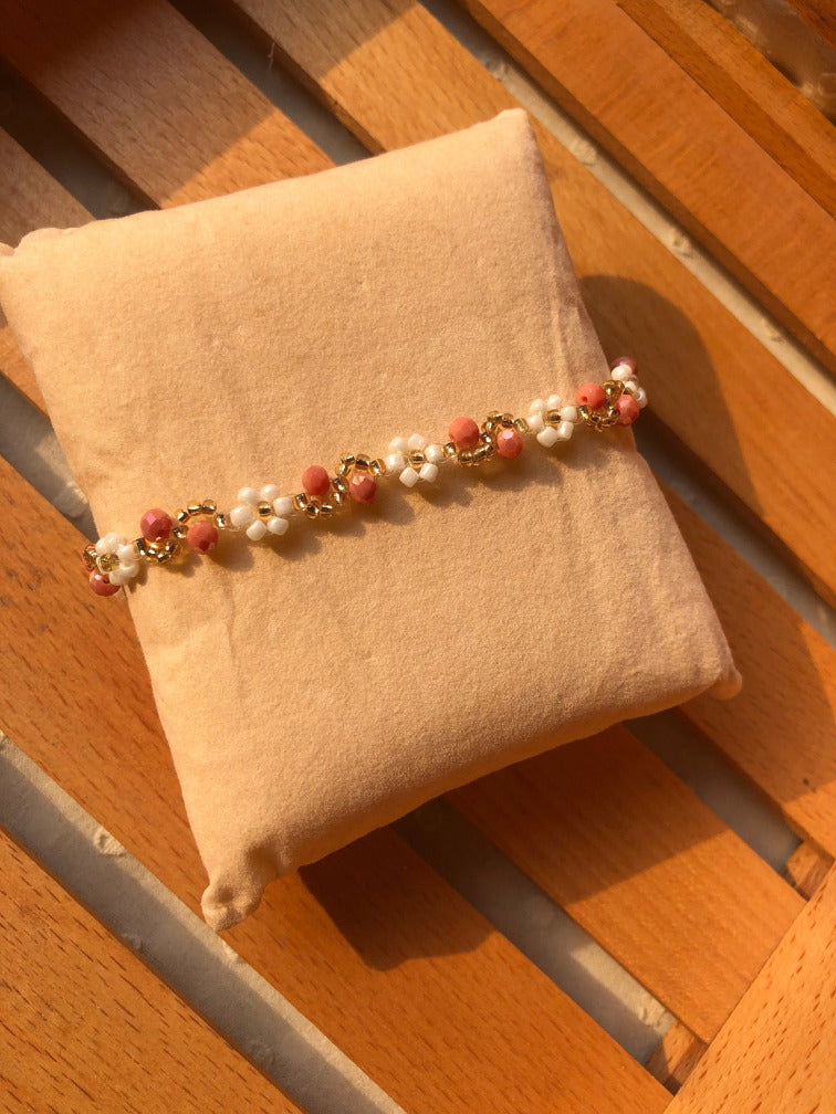 Close-up of white seed bead daisy flowers alternating with coral pink faceted beads